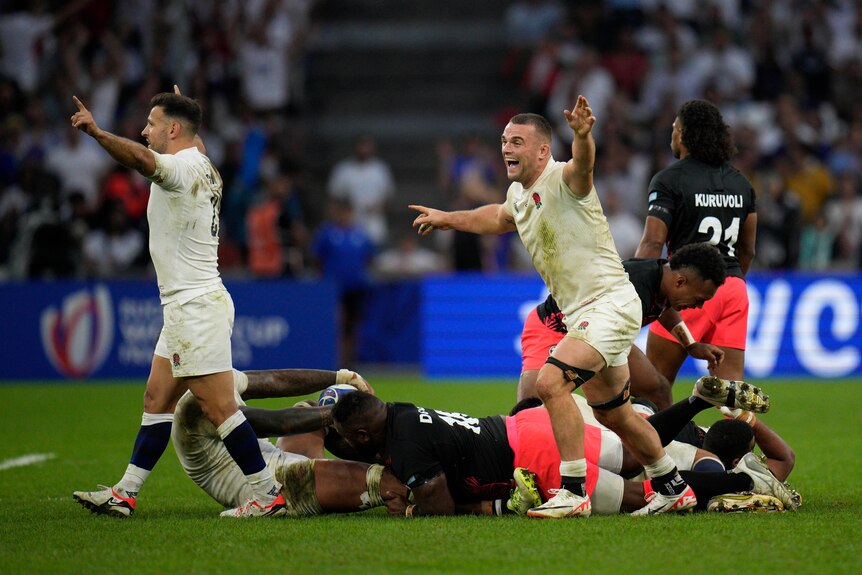 An English rugby union player shouts in celebration with arms raised as he begins to run after the final whistle.