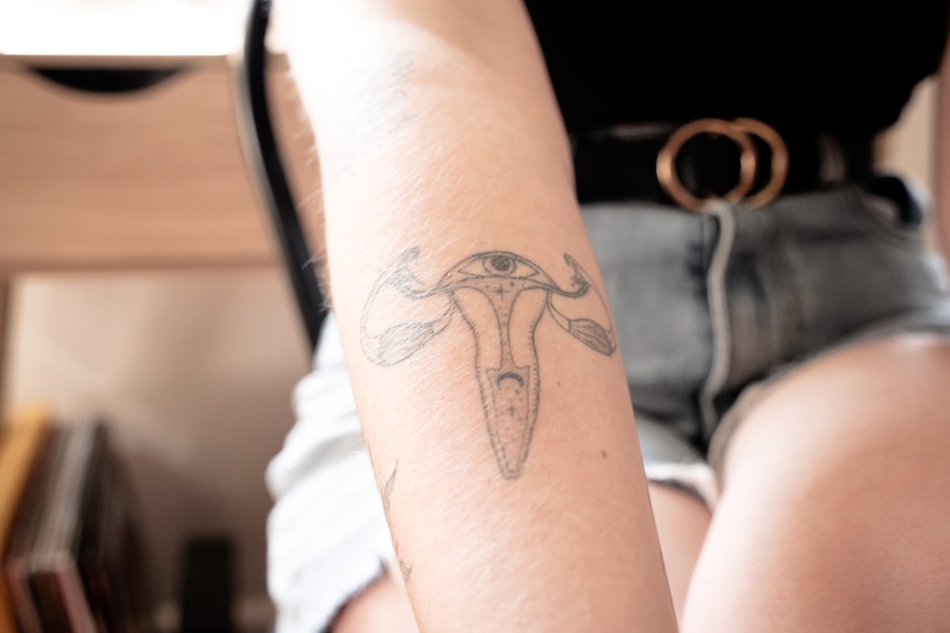 Tattoo on arm in the shape of a female reproductive system.