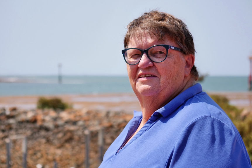 A woman wearing glasses with the Port Hedland port in the background.