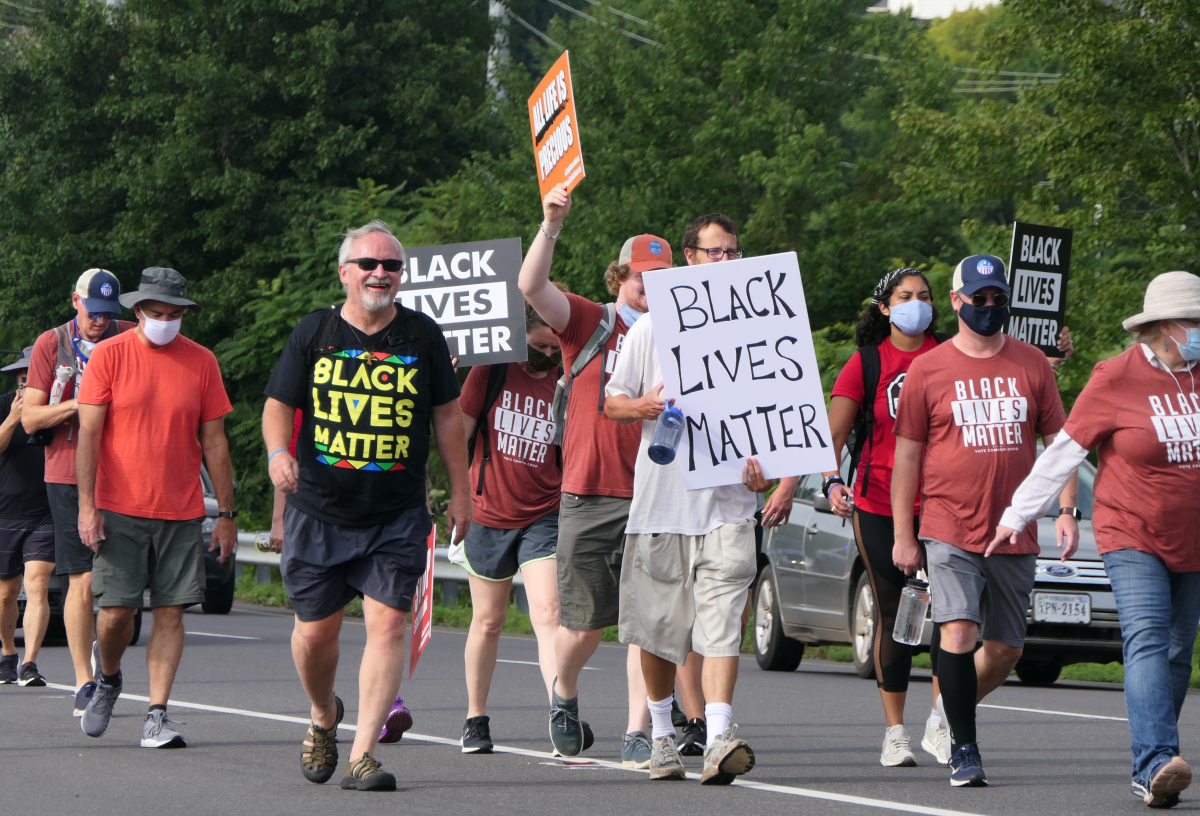 The Rev. Keith Mannes, in a Black Lives Matter T-shirt, walks with protesters.