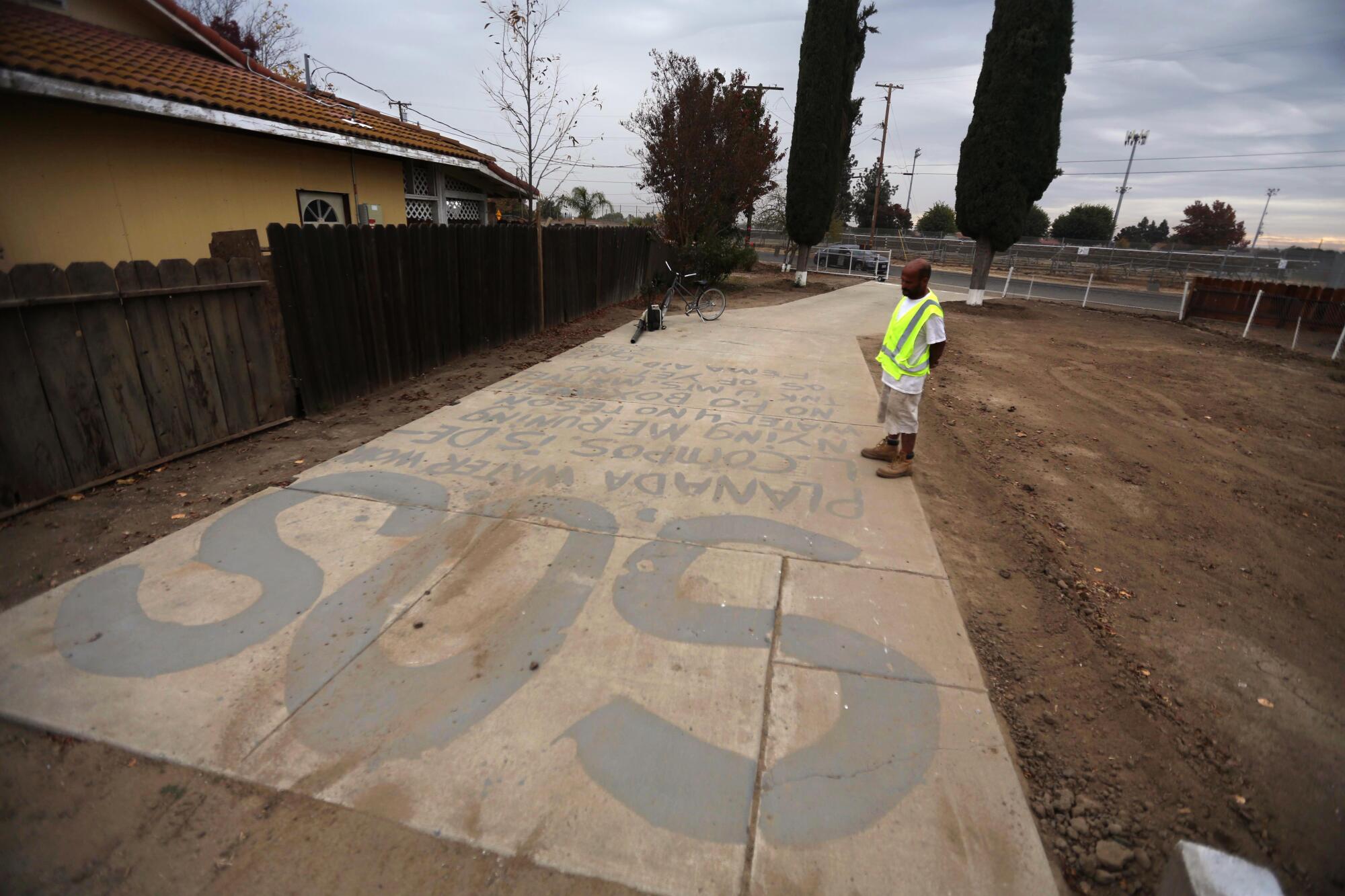 A man stands on a driveway emblazoned with SOS. 