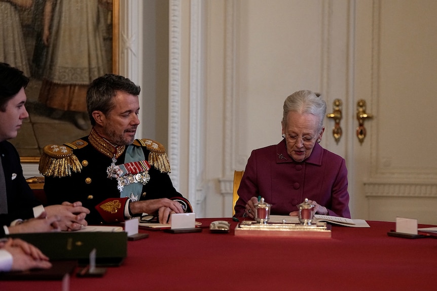 Queen Margrethe signs abdication papers with Frederik looking on alongside his son Christian.