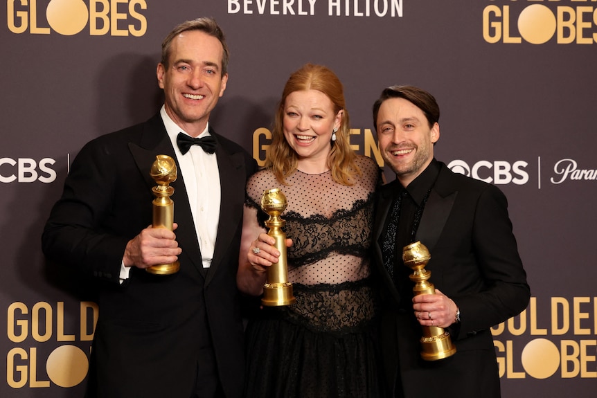 Sarah Snook, Matthew Macfadyen, and Kieran Culkin holding Golden Globe awards, dressed in black formal gear, smiling