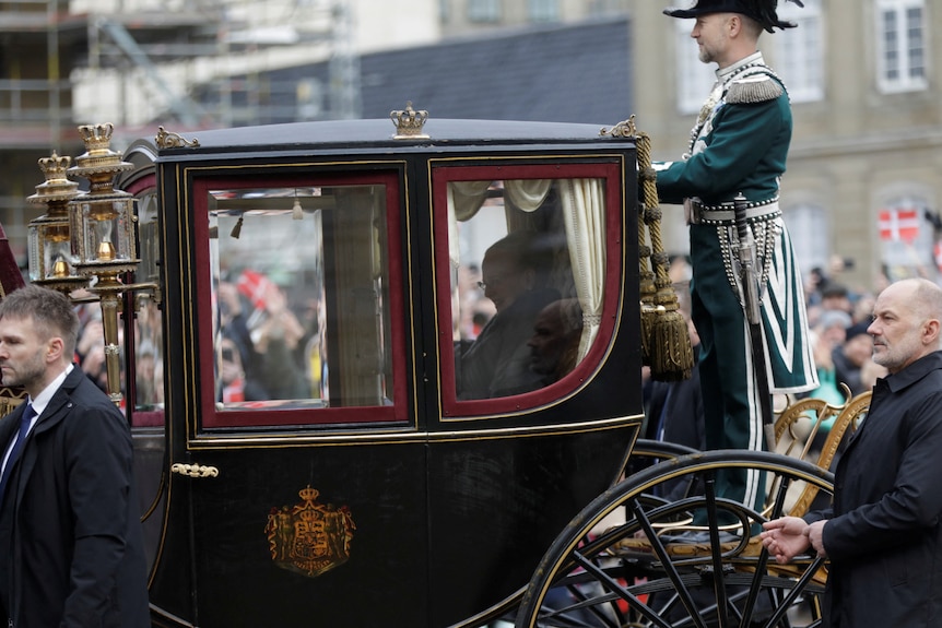 Queen Margrethe in a horse-drawn carriage outside palace.