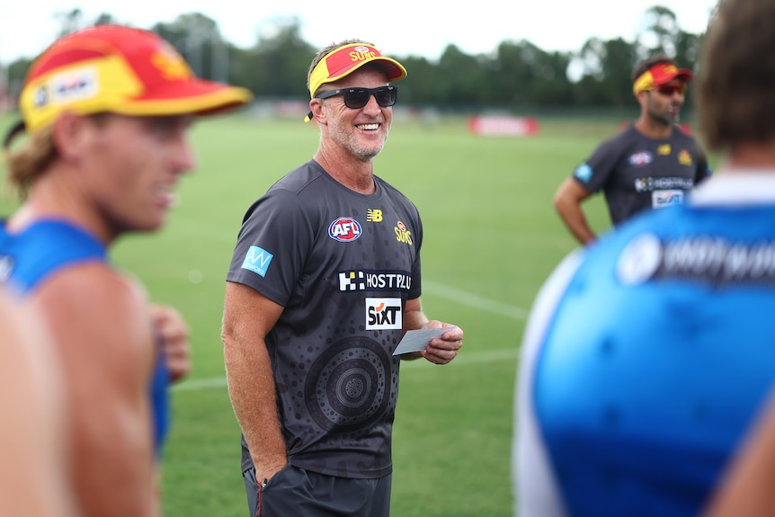 Damien Hardwick laughs with Gold Coast Suns AFL players at a training session.