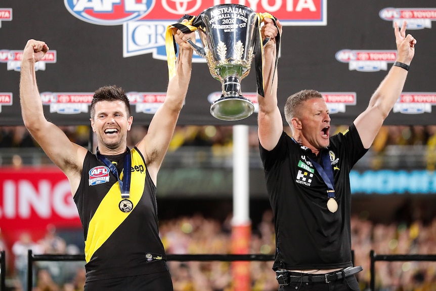 Trent Cotchin and Damien Hardwick lift the 2020 AFL premiership trophy.