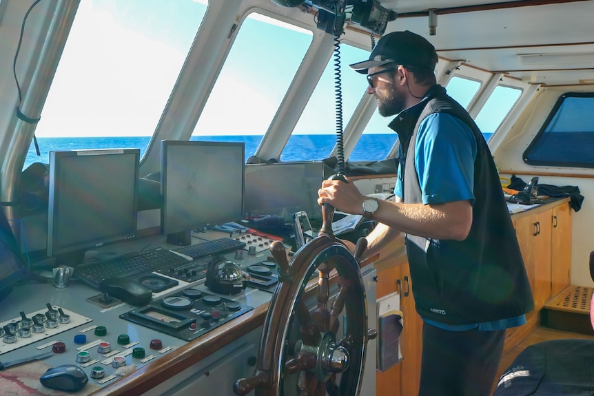A man at the helm of a boat.