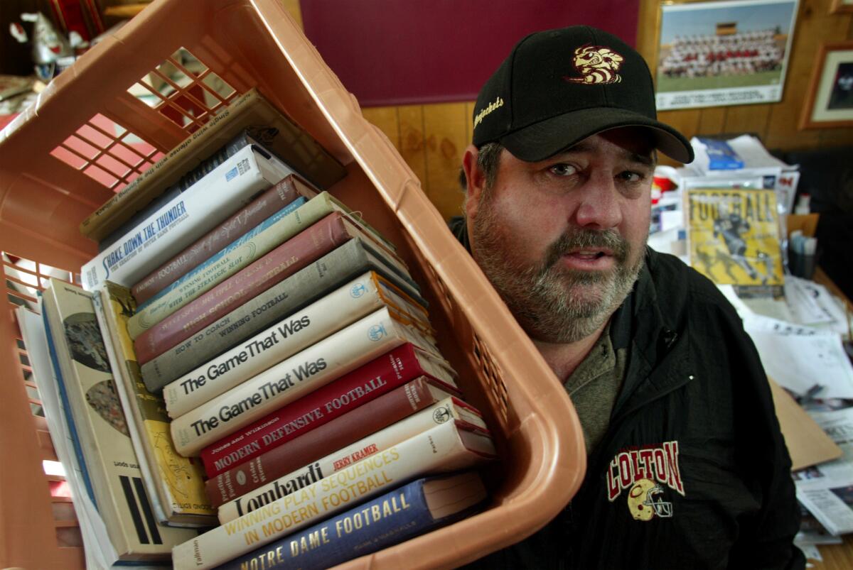 Colton High football coach Harold Strauss with a collection of playbooks.