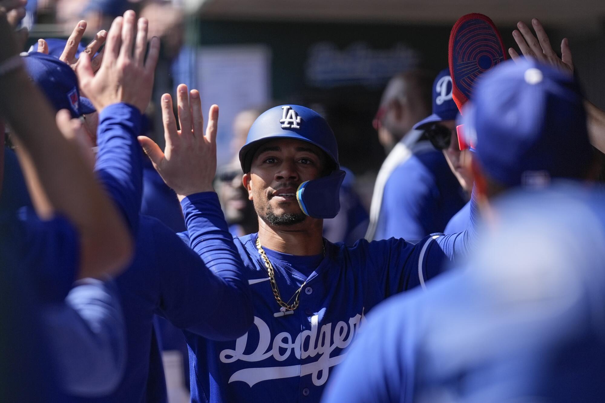 The Dodgers' Mookie Betts high-fives teammates and celebrates after scoring.