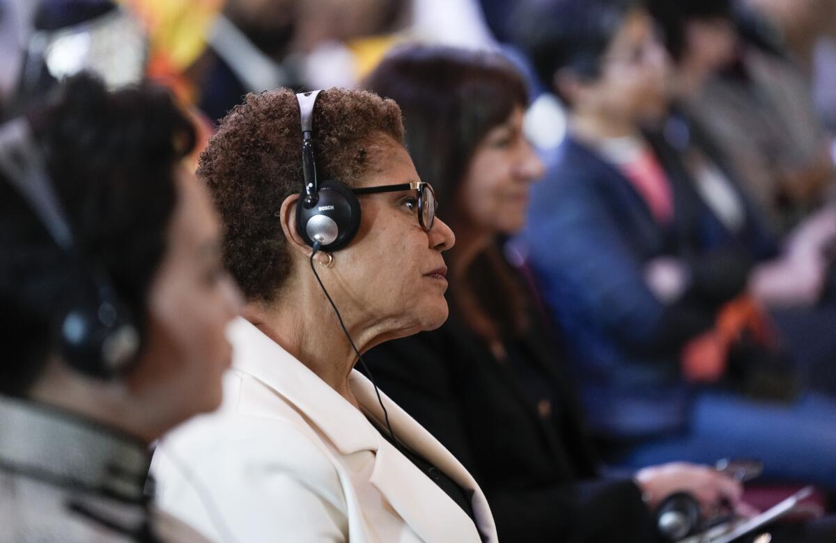 Los Angeles Mayor Karen Bass seated among women, wearing headphones