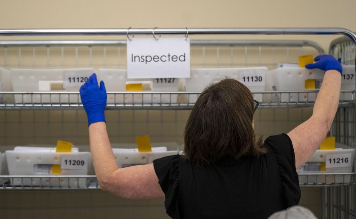 Erin Kane collects ballots for inspection at the office of the San Joaquin County registrar of voters.
