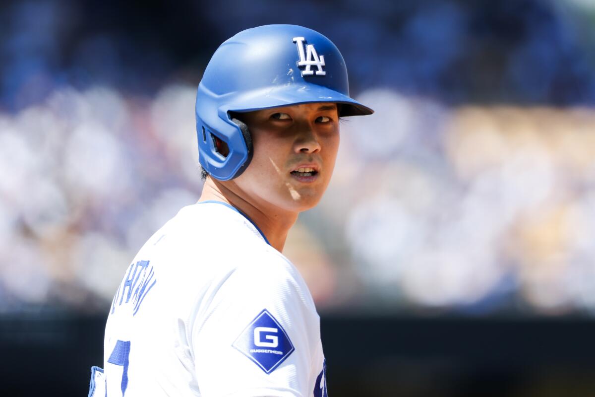 Dodgers star Shohei Ohtani looks back from first base after hitting a single.