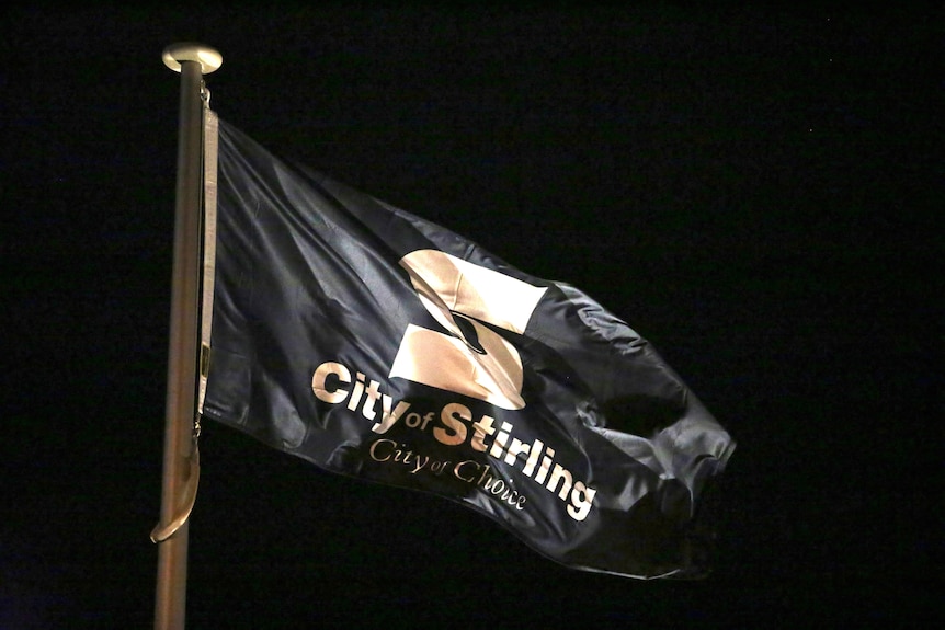 A CIty of Stirling flag flying at night.