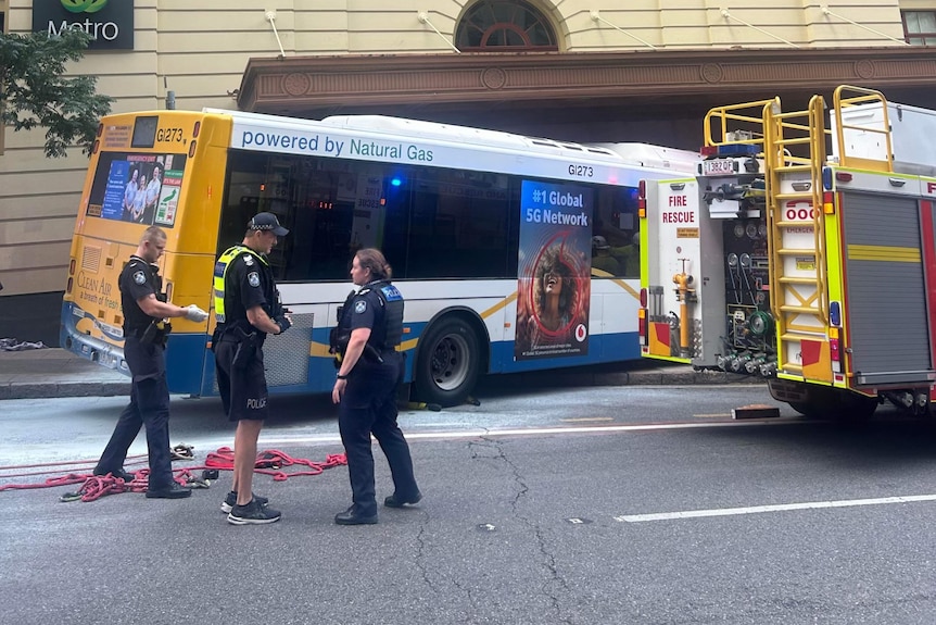 A fire truck is parked near a bus that has mounted the sidewalk.