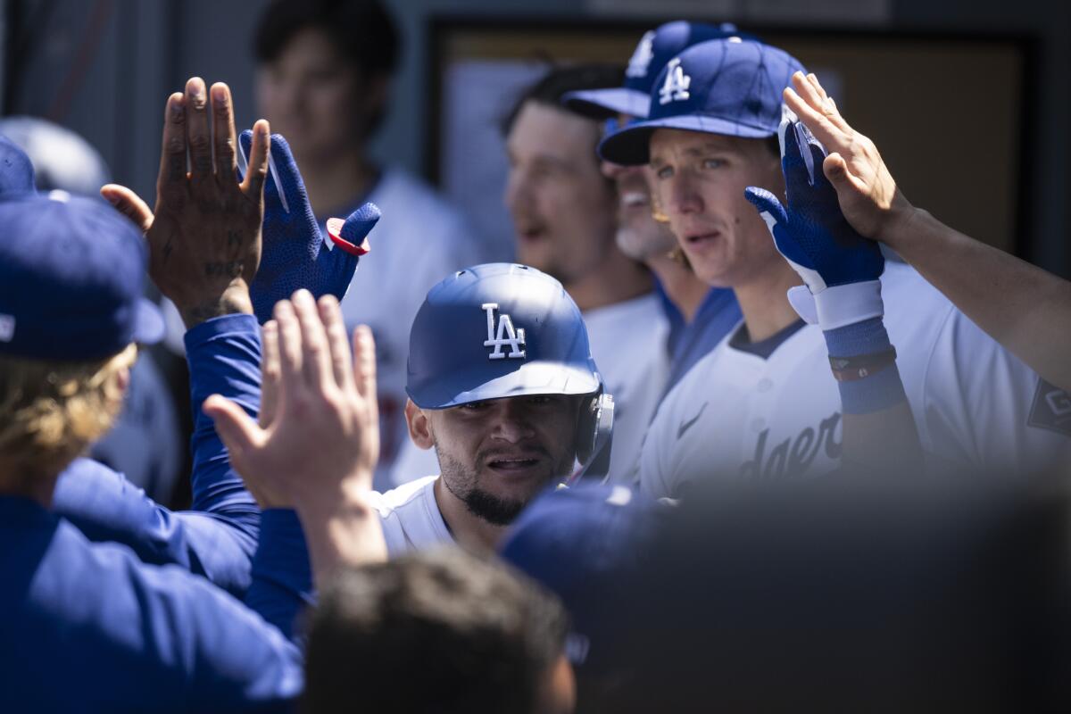 Andy Pages high-fives teammates in the Dodgers dugout after hitting a three-run home run.