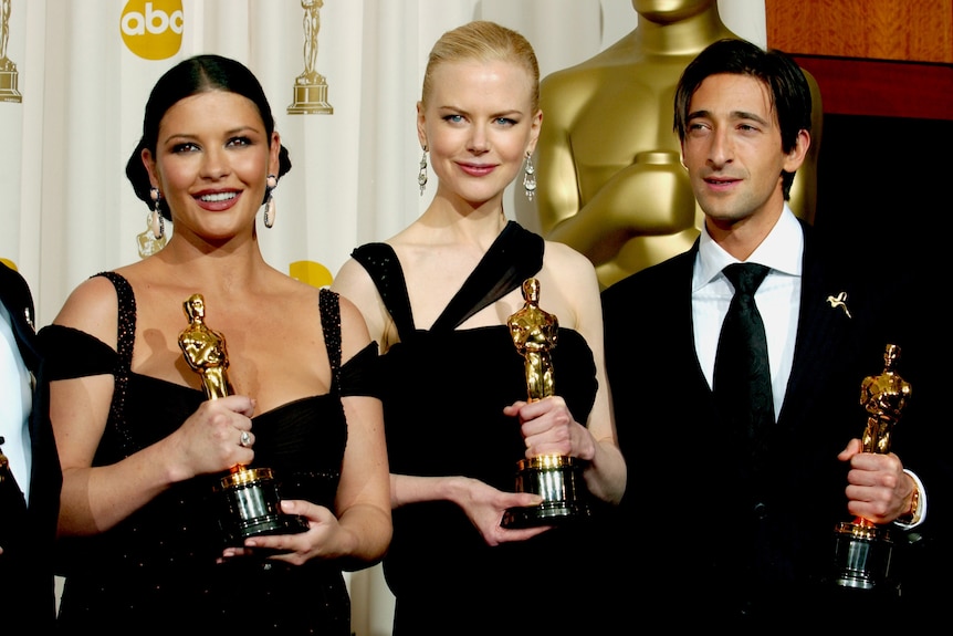 Two women in evening gowns in black, nicole kidman blonde in centre and a man in tux to the side. All hold oscar awards