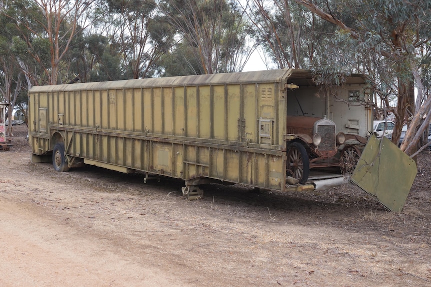 A green rectangular missile box sits idle with an old Ford poking out the end