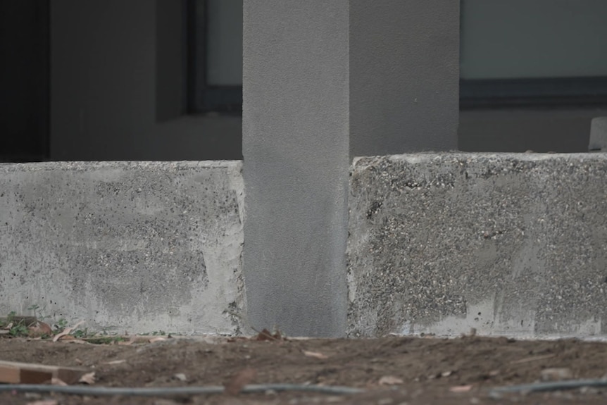 Different coloured concrete wraps around a post.