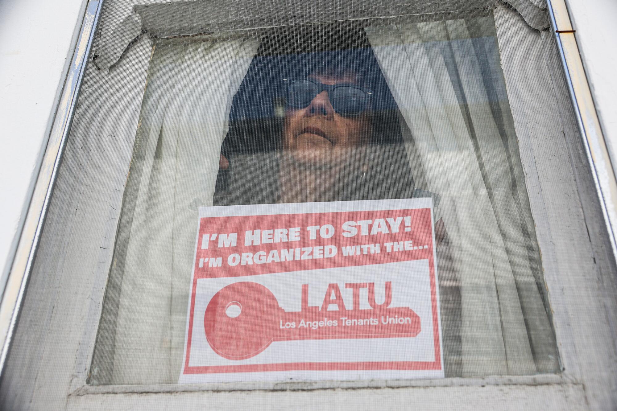 Tenant Sally Juarez has a sign displaying the support she receives from the Los Angeles Tenants Union.