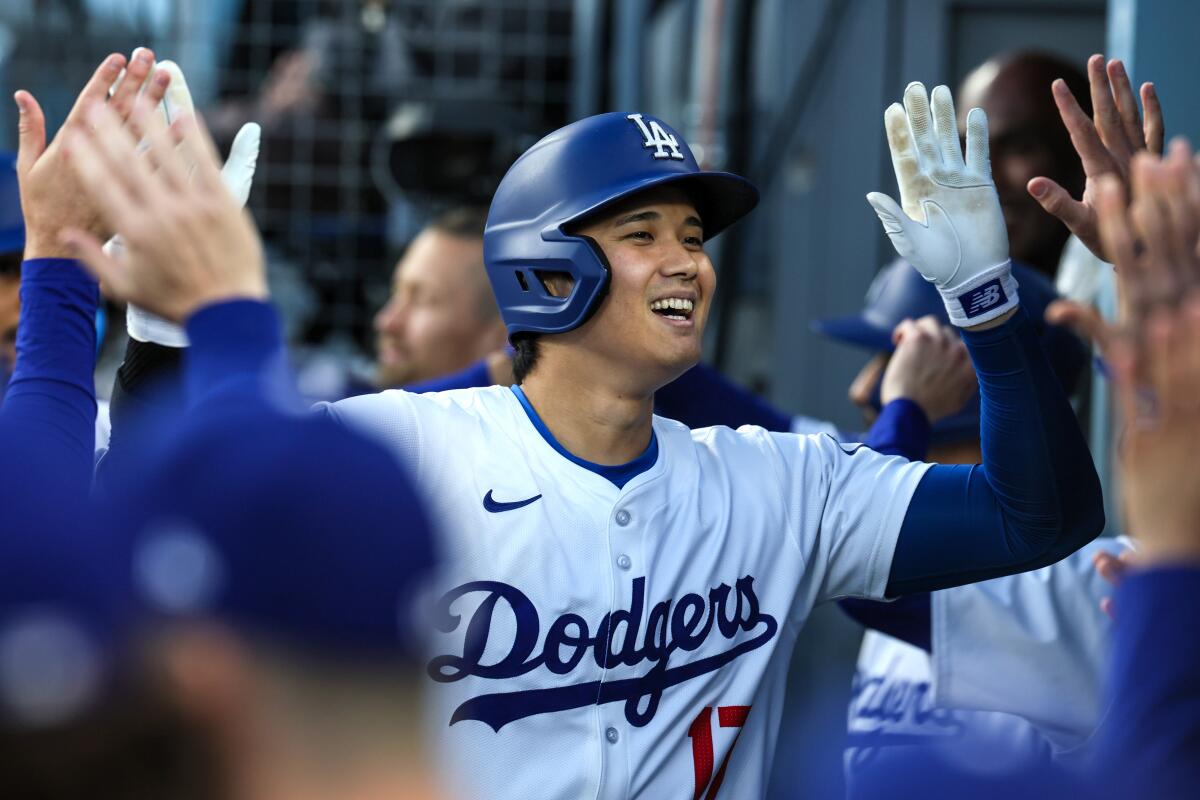 Dodgers star Shohei Ohtani celebrates in the dugout after hitting a two-run home run in the first inning Monday.