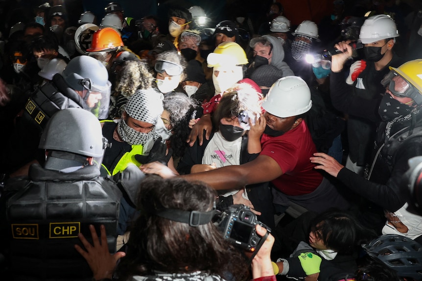 Police scuffle with protestors in a tight group