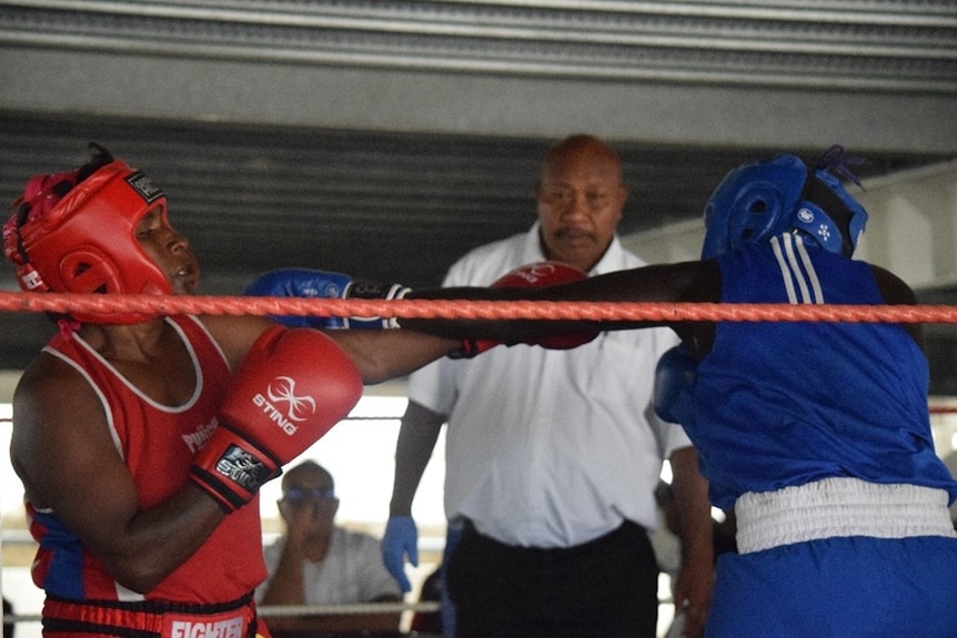 Two female boxers from Papua New Guinea exchange punches in the ring. 