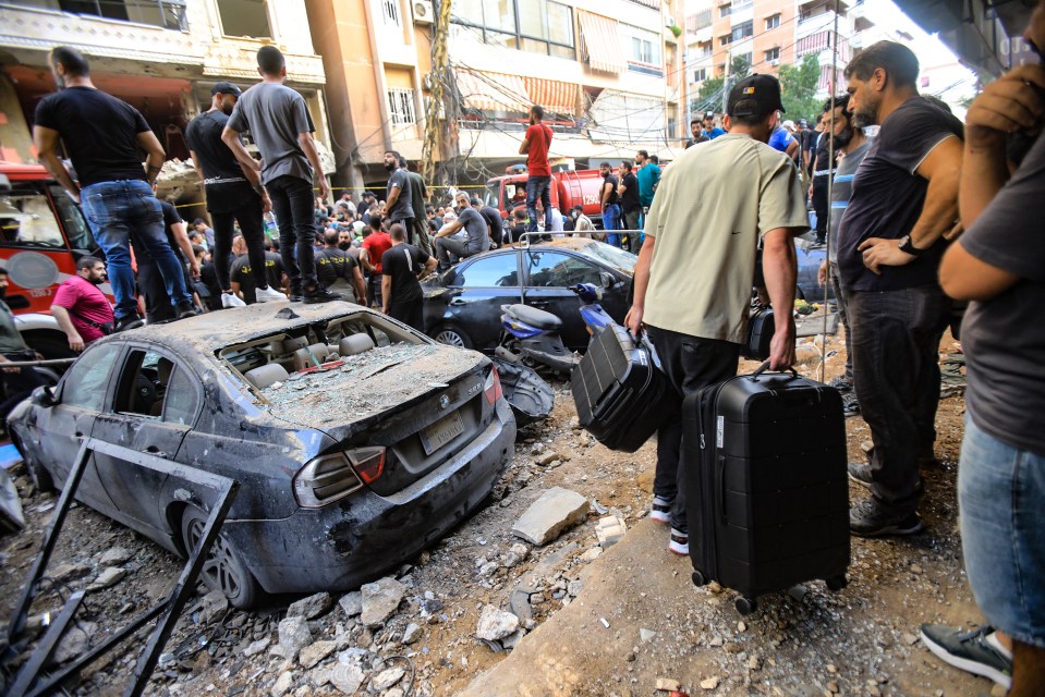 People stand on cars which were hit with flying debris in the air attack