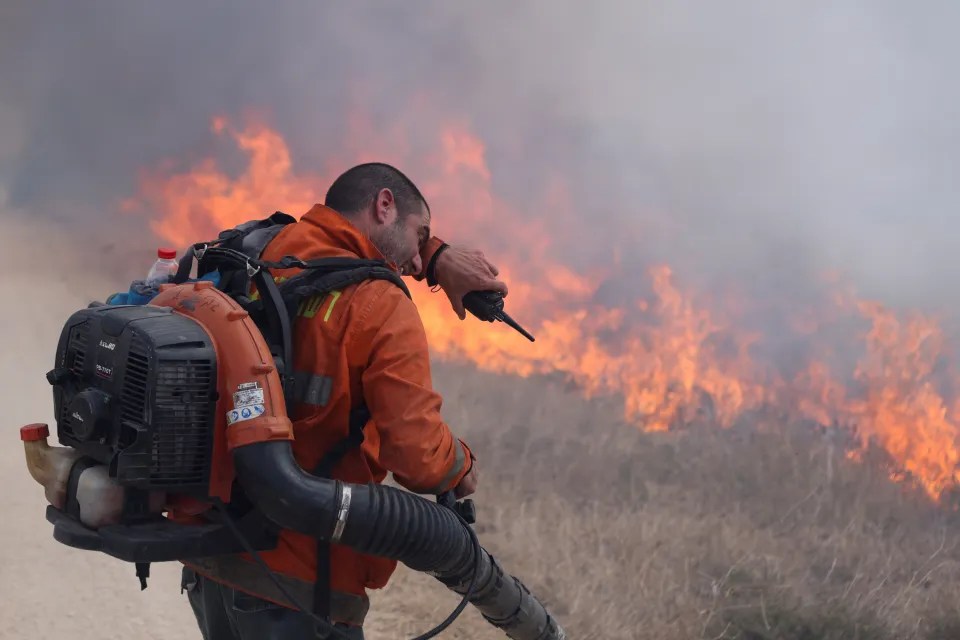 A firefighter battles against flames near to Golan Heights following a rocket attack from Lebanon