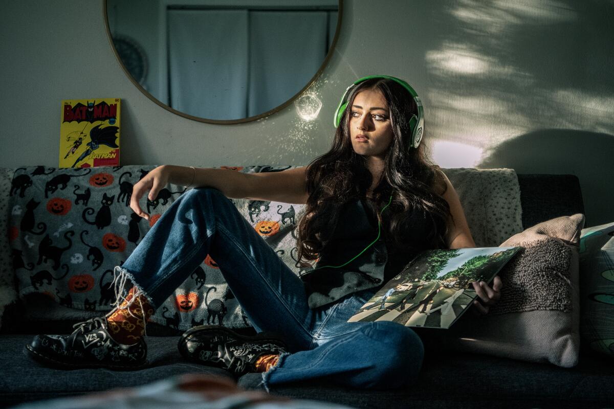 A girl wearing headphones sits on a couch.