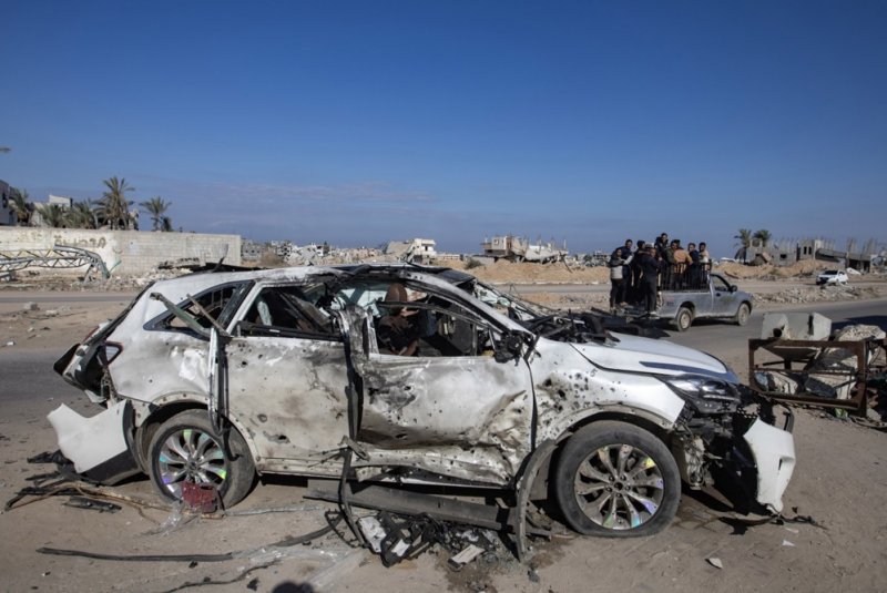 Palestinians inspect a destroyed vehicle on Salah al-Din Road following Israeli military strikes, east of Khan Yunis, southern Gaza Strip on Saturday. Photo by Haitham Imad/EPA-EFE