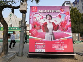 Pedestrians walk near an advertisement promoting a sales festival in Beijing, Thursday, Nov. 7, 2024.