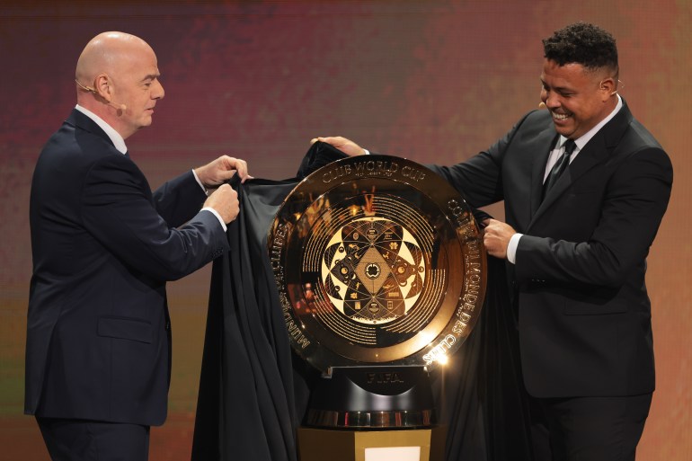 Dec 5, 2024; Miami, FL, USA; FIFA president Gianni Infantino (left) and Brazilian former soccer player Ronaldo Nazario unveil the FIFA Club World Cup trophy during the Club World Cup draw at Telemundo Studios. Mandatory Credit: Sam Navarro-Imagn Images
