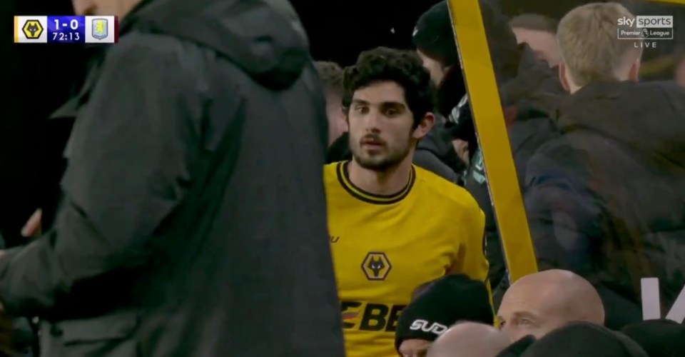 A soccer player in a yellow jersey stands amongst other people.