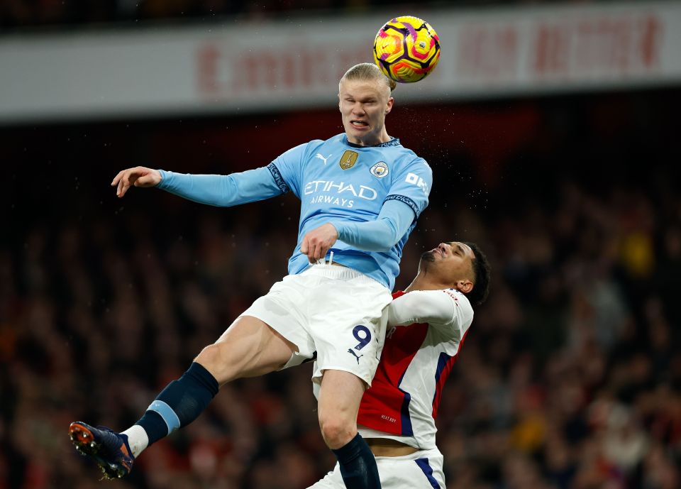 Erling Haaland of Manchester City heads the ball over William Saliba of Arsenal.