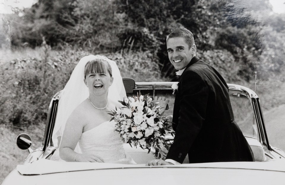 Black and white photo of a bride and groom in a convertible car on their wedding day.