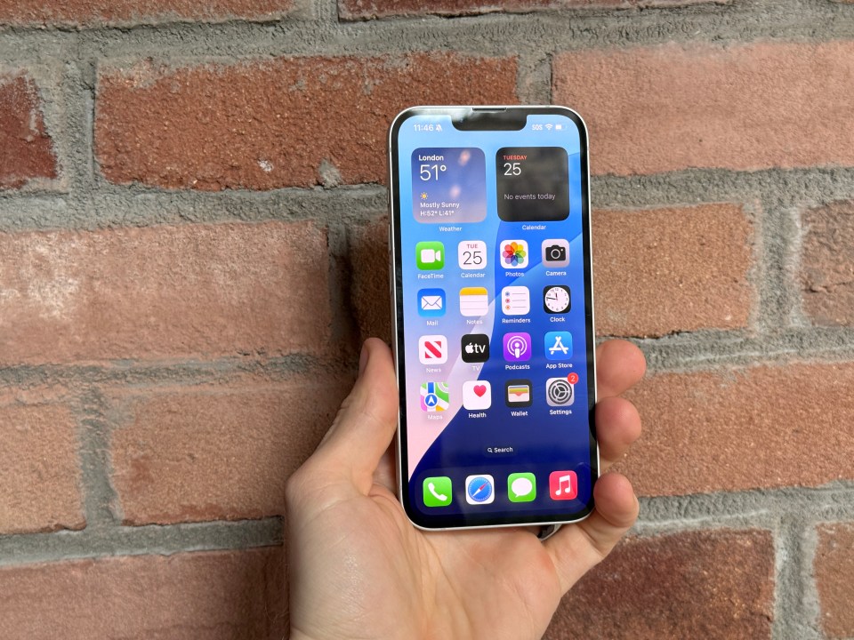 Hand holding iPhone displaying apps and weather.