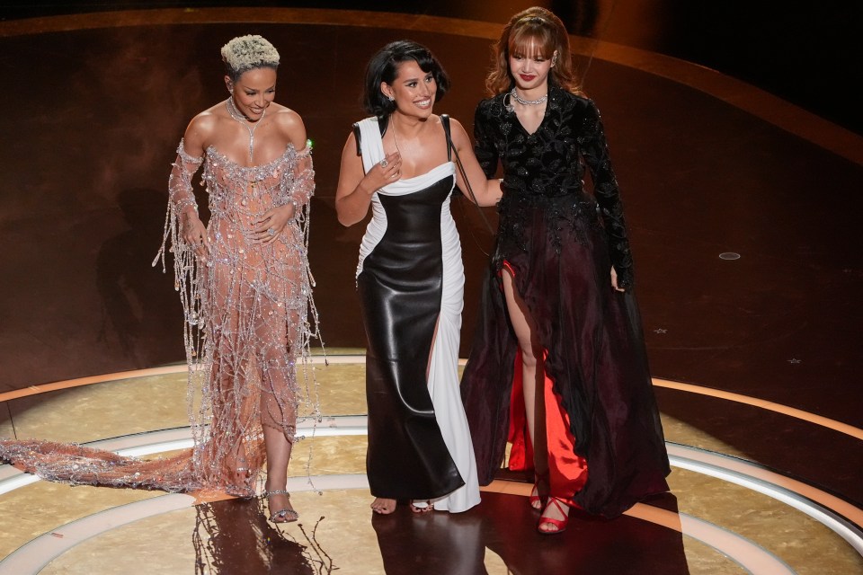 Doja Cat, Raye, and Lisa on stage at an awards ceremony.