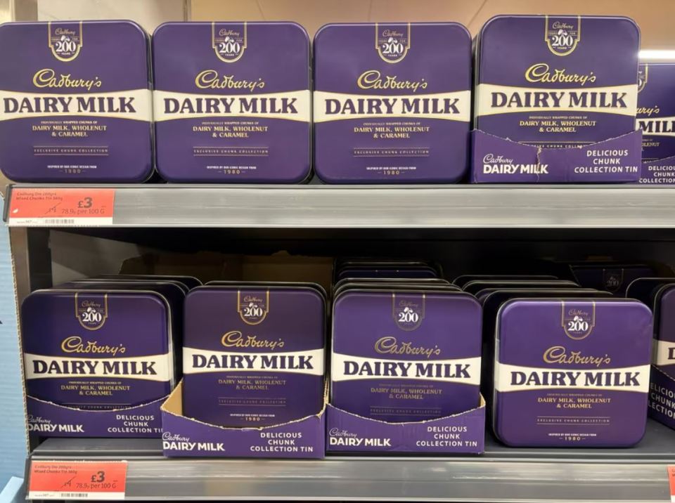Cadbury Dairy Milk chocolate tins on a shelf.