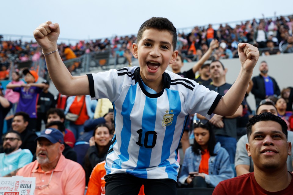 Young boy in Argentina jersey cheering at a soccer game.