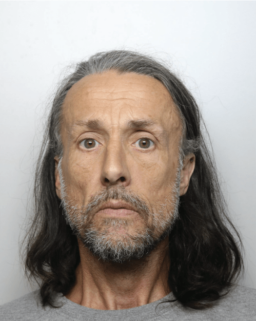 Mugshot of a man with long graying brown hair and a goatee.