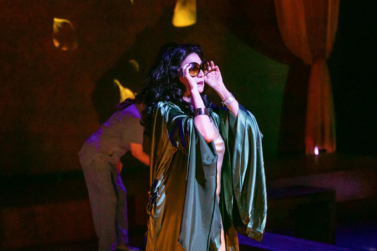 Evelina Fernandez stands onstage, adjusting her sunglasses