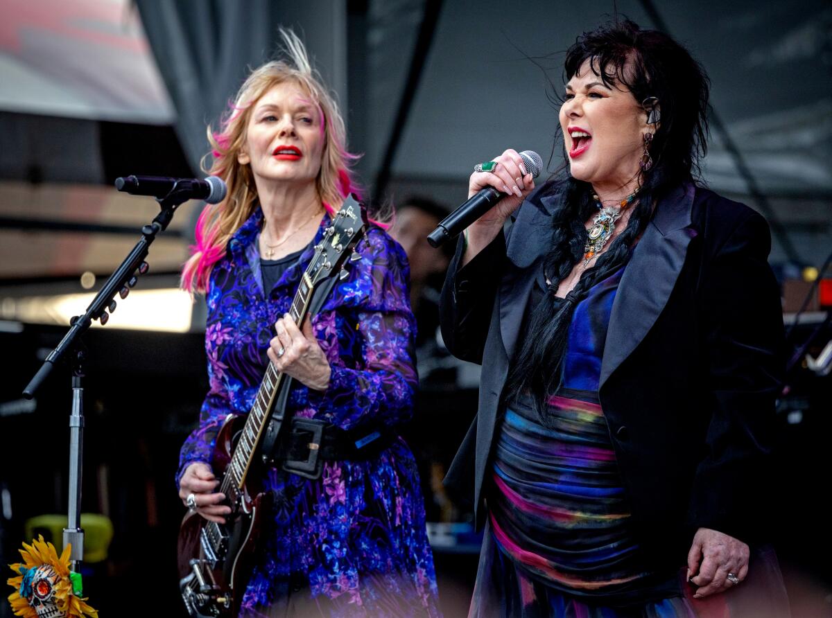 Two women onstage, one playing guitar, the other singing into a microphone