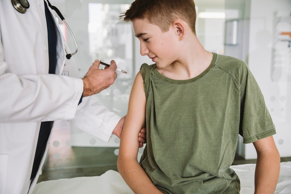 A doctor giving a teenage boy a vaccination.