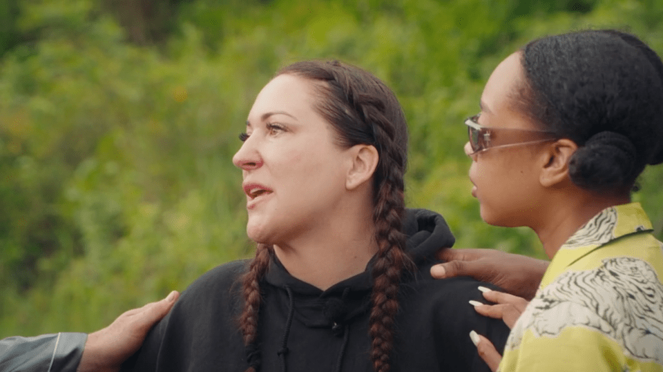 Screenshot of two women talking outdoors, one consoling the other.