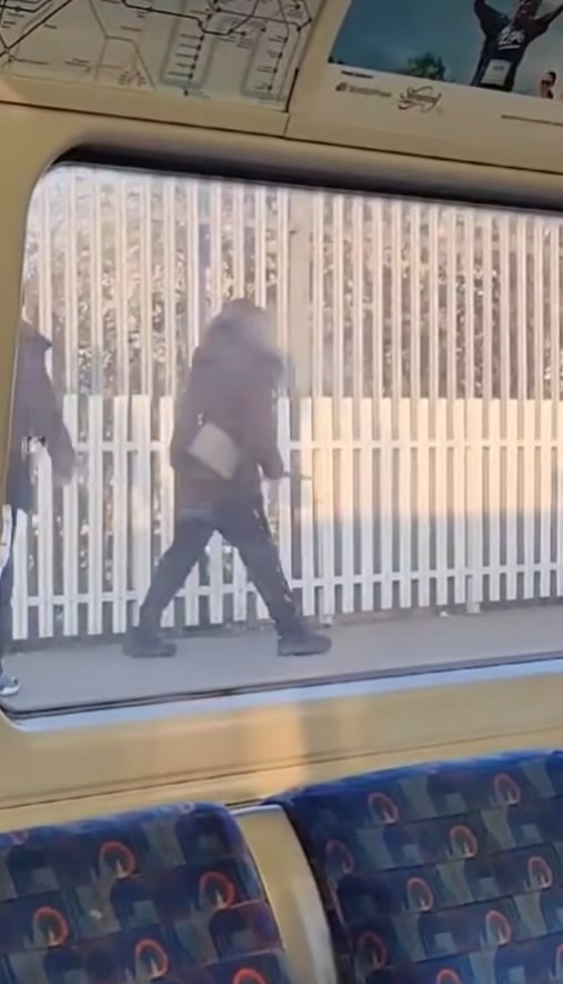 View from a train of people walking past a fence.