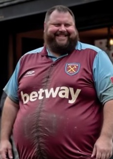 A large man wearing a West Ham jersey.