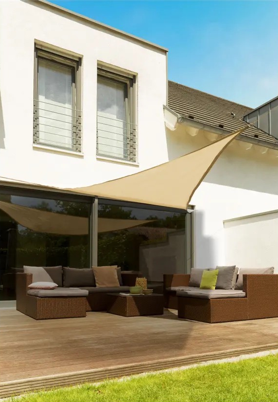 Beige triangular sun shade sail over patio furniture.