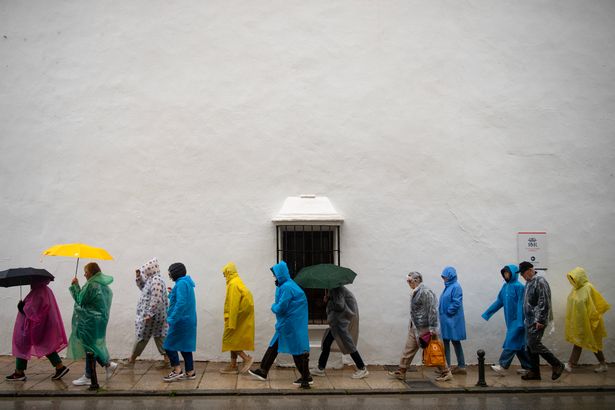 People use rain covers and umbrellas during heavy rain in Ronda, southern Spain, on March 17, 2025
