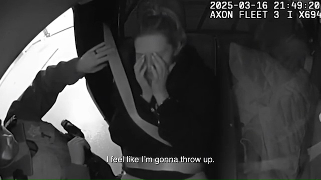 Black and white police bodycam footage of a woman crying and saying, "I feel like I'm gonna throw up."