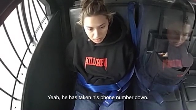 A teacher restrained in the back of a police car.
